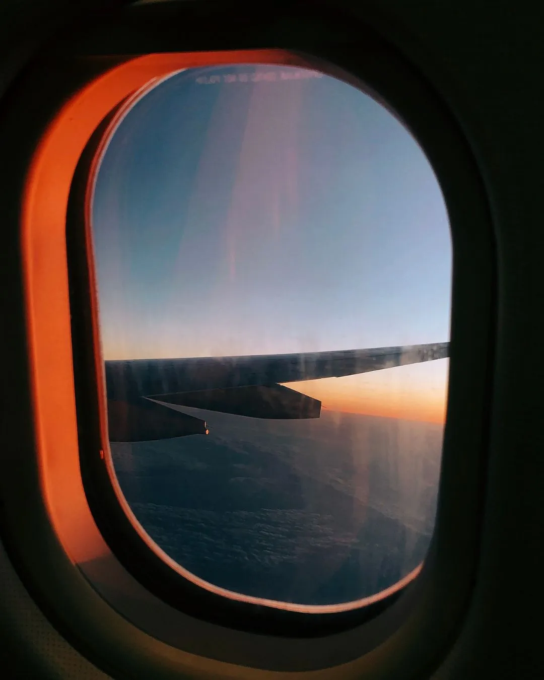 Blick aus einem Flugzeugfenster über die Wolken bei Sonnenuntergang
